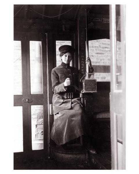 A ticket collector for the Milwaukee Electric Railway is sitting at her station.