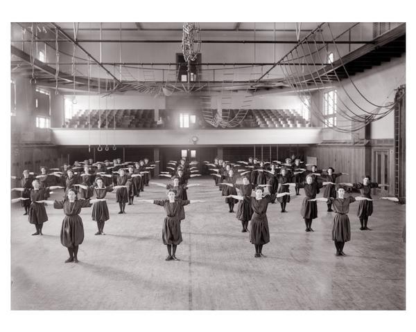 A group of female students wearing sports uniforms, participating in exercises as part of their physical education curriculum. Lathrop Hall, University of Wisconsin-Madison.