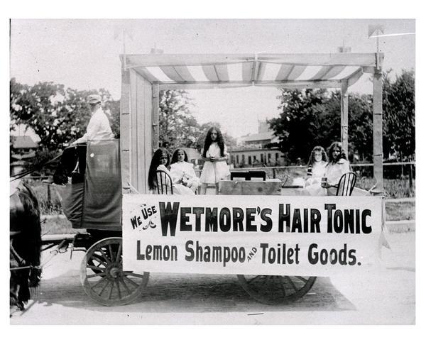 A traveling medicine wagon with saleswomen and vendor selling Westmore's Hair Tonic.