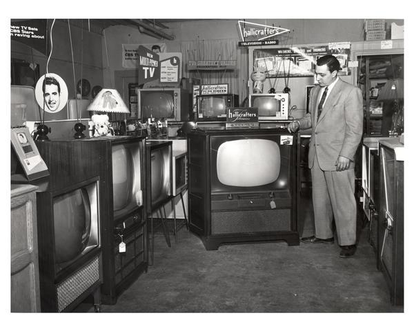 Television salesperson Sam Carrao posed with display of new merchandise at The TV Center,  914 Main Street in Green Bay.