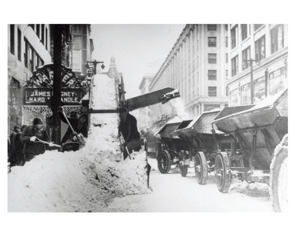 Winter scene showing snow removal vehicles working to clear the snow on Wisconsin Avenue in Milwaukee after a winter blizzard.