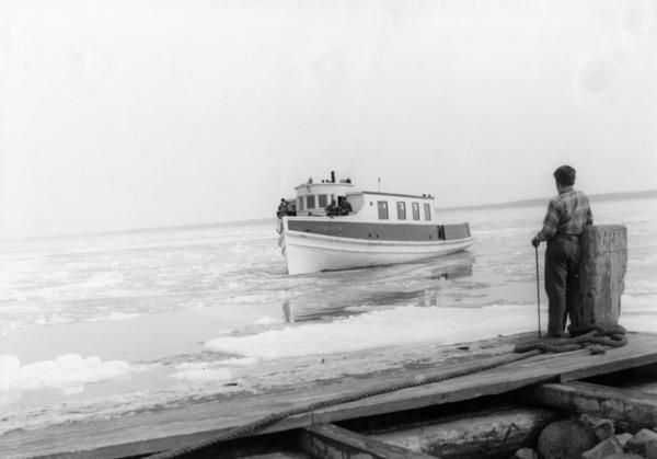 Man standing on dock watching the ferry "Gar-How" coming to dock on the first trip in spring.