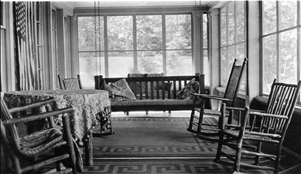 Enclosed porch of Hull Cottage showing "rustic" log furniture as well as a Mission Style porch swing and Arts & Crafts area rugs. The Hull cottage, a.k.a. Coole Park Manor, later became known as Chateau Madeline.