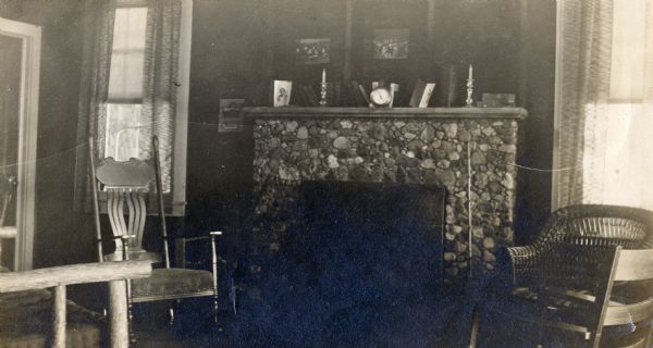 Living room interior of Madeline Island vacation house showing stone fireplace and furniture. The house belonged to the Baker family and later became the home of Hamelton Nelson Ross.