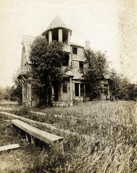 A dilapidated Cedar Bark Lodge with no glass in the windows and an overgrown yard on Hermit Island.