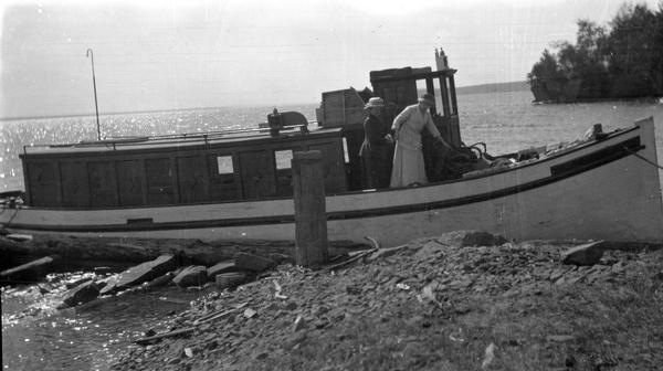 Two women aboard the Hull family boat, the "Lizzie W.," while it is tied to shore at one of the Apostle Islands.