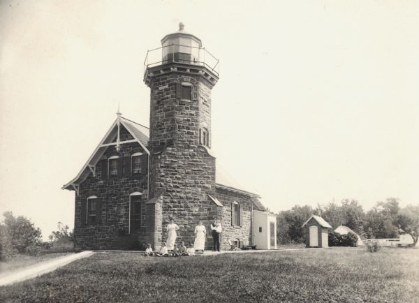 Sand Island Lighthouse on Apostle Island, Lake Superior. Lighthouse keeper and family are posing in the front of the building.
