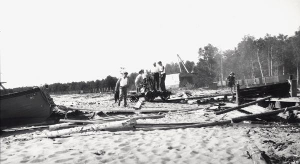 Men and boys are on a hand-pump rail cart on a Michigan Island beach, Lake Superior. A young girl is walking on the right.