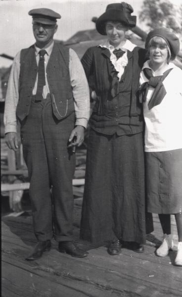 Captain Dan Angus stands next to Elsie Tough, and adolescent Anne Ashley, on a dock on one of the Apostle Islands.