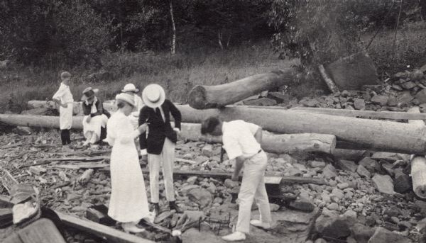 Group of people on an Apostle Island log-strewn beach. Outing included Johnie Webb, Mrs. Webb, Herbert Turman and Herbert Rogers.