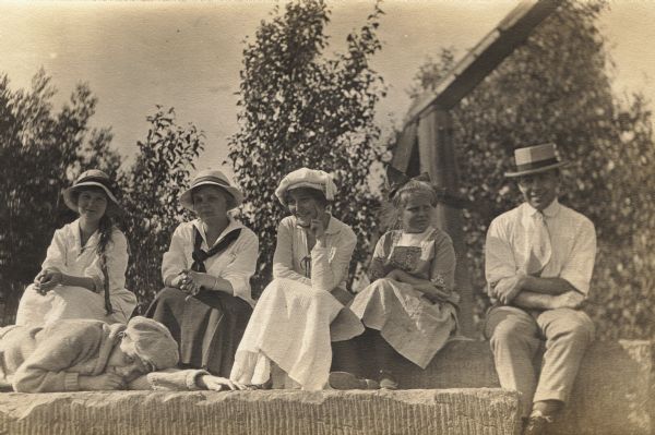 Group of people sitting on sandstone on Basswood Island, Apostle Islands. People from l. to r.: E.H., Florence Baker, Dot Ross, Louise Baker, Harie Ross, and Bill Baker (lying in front).