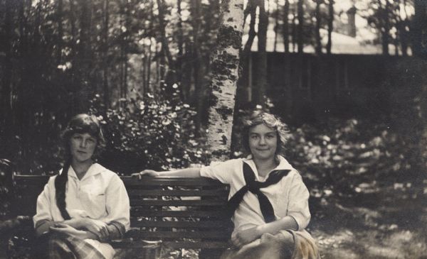 Elizabeth Hull & Elizabeth Nesbit, sit outside on a bench on Madeline Island.