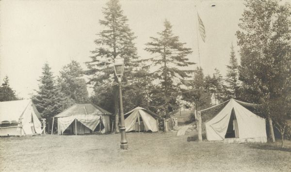 Camp Stella on Sand Island of the Apostle Islands. View includes tents, lamp post, bridge and flag pole.