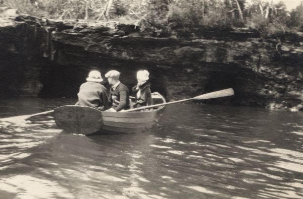 Man in a rowboat with two women along the shoreline of Lake Superior.