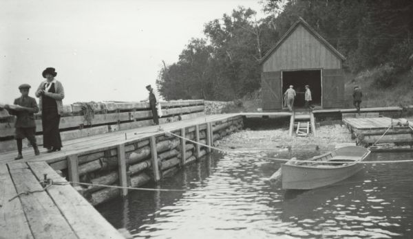 Boathouse, dock and boat at Devils Island Light Station. Bill Baker, Elsie Tough, and Captain Angus.