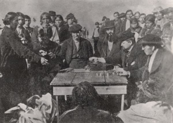 Indians receiving payment. Seated on the right is John W. Bell. Others are, left to right, Asaph Whittlesey, Agent Henry C. Gilbert, and William S. Warren (son of Truman Warren).