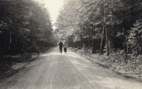 A couple strolling down the main road, through the woods, to the mission on Madeline Island.