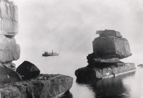 Rock formation, The Sphinx, on Stockton Island of the Apostle Islands. Steamer "Edna" in background on Lake Superior.
