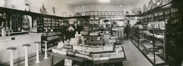 Panoramic view showcasing impressive candy displays and a soda fountain in Tompkin's Drugstore on 63rd street.