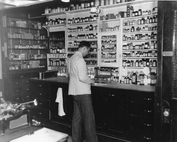 Pharmacist Roy Bird Cook prepares medicinal powders to be weighed for a prescription.