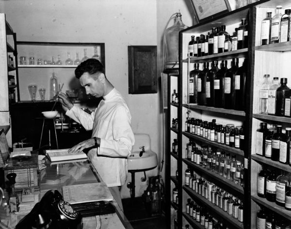 Pharmacist Roy Wilkinson follows the instructions in his manual on how to precisely heat and stir a medicinal mixture.