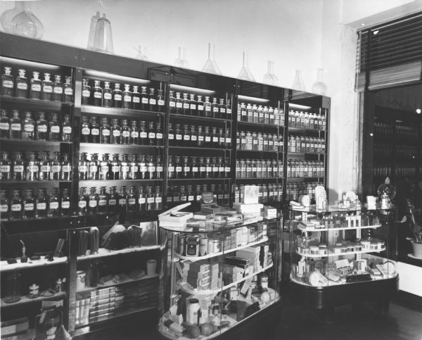 Interior view of Helen Rosenbaum's Pharmacy. The shelves contain rows of traditional glass pharmaceutical bottles.