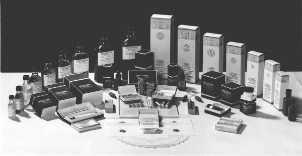 A display of various medical containers including glass bottles, boxes, and pill containers, all emblazoned with the logo for the Professional Pharmacy in Salt Lake City.