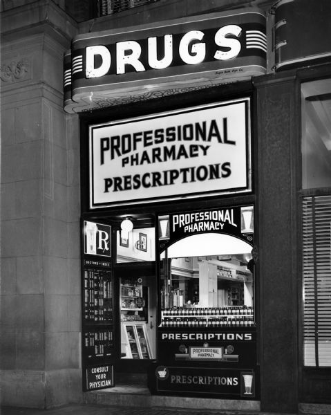 A view of the storefront of the Professional Pharmacy in Salt Lake City. Beside the entrance is an index of local physicians for customer use.
