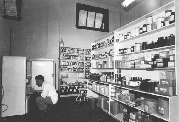 A druggist checks the supplies in the biologicals refrigerator.