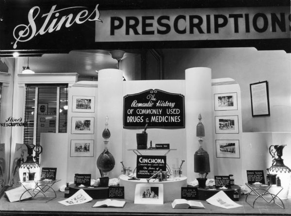 Artfullly arranged window display at Stine's Prescription Pharmacy, featuring "The Romantic History of Commonly Used Medicines". Cinchona is featured prominently.