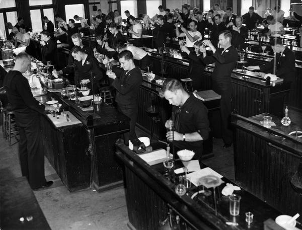 Students from the U.S. Coast Guard Hospital Corps School perform practical experiments for the chemistry phase of their course. The officer in charge of the University of Columbia contingent was pharmacist R.J. Bussey. He was assisted by three Chief Pharmacist Mates from the service, who acted as instructors, assisting the regular school faculty.