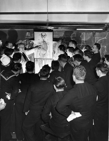 The class of U.S. Coast Guard Hospital Corps School Pharmacists' Mates-to-be is introduced to the skeleton of the human body as part of their studies of anatomy and physiology. The setting of broken bones is one of the jobs they performed in emergencies at sea.