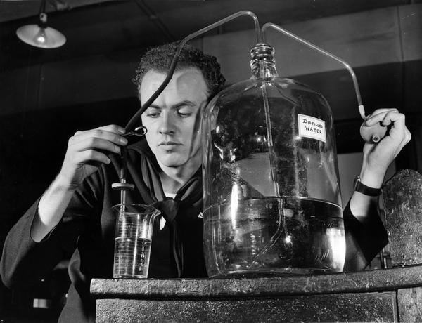 This student of the U.S. Coast Guard Hospital Corps School is carefully measuring out a quantity of distilled water for a prescription. Distilled water is a requirement of the U.S. Pharmacopeia for medicinal use. All medicines must conform to the standards set forth in the Pharmacopeia.