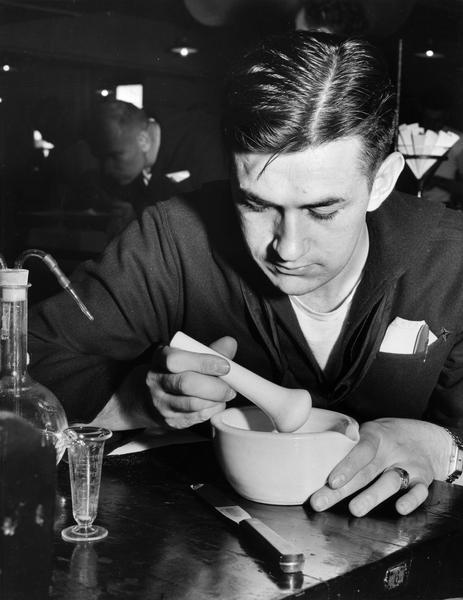 A member of the U.S. Coast Guard Hospital Corps School uses the traditional pharmacist's tool of a mortar & pestle to grind medicinal ingredients for a prescription.