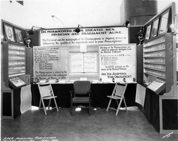 A view of the U.S. Pharmacopeia's exhibit at the American Medical Association's 1931 Conference in Kansas City. The exhibit includes printed reference materials, portraits of founding delegates, several pharmaceutical showglobes, as well as an impressive selection of bottled medications.