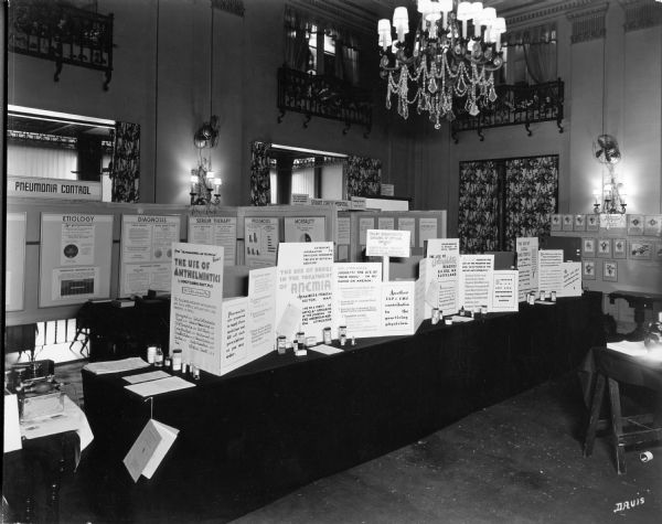 View of the U.S. Pharmacopeia's exhibit at the 1937 meeting of the American Medical Association. The exhibit highlights various advancements in drug treatment, including the use of anthelmintics and antisyphilitic remedies.