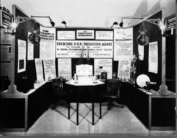 View of an U.S. Pharmacopeia exhibit at the 1931 American Medical Association Conference. The exhibit showcases hypnotics, digitalis, analgesics, and iodine, among others.
