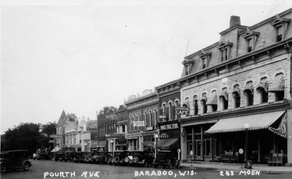View across street towards a row of businesses on Fourth Avenue, including Warren Cafe, Wang's Rexall Drug Store, Wisconsin Power & Light, a restaurant, and a hotel. Caption reads: "Fourth Ave Baraboo, Wis."