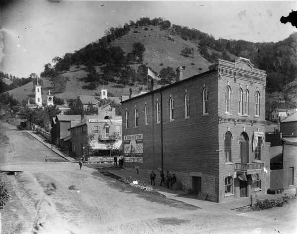 View looking east on Liberty Street from Shore Drive. In the foregound is the F. Bohri & Son Clothing store, and behind it is a store selling "Drugs, Medicines, Books & Stationary".