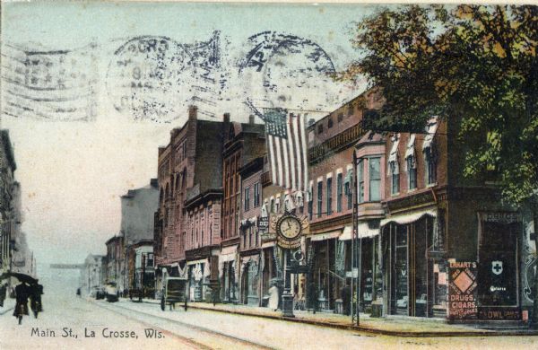 View of a row of businesses on Main Street. Erhart's Drugstore is on the left, and advertises film and cigars, in addition to drugs. W.T. Irvine, optician, is located next door.