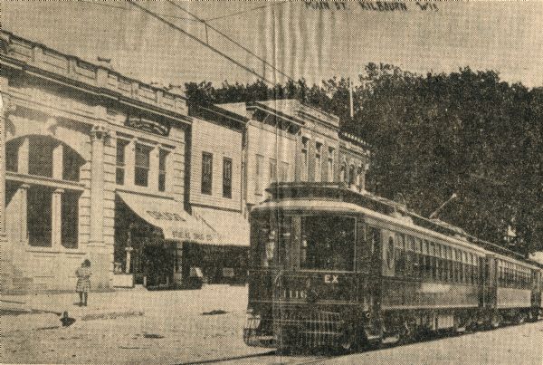 A streetcar apparently zips along down the center of Broadway, the town's main thoroughfare. The structure with the awning (to the right of the old bank building) was occupied by Stuelke's Drug Store when this photograph was taken. This car (1116) was part of The Milwaukee Electric Railway & Light Company's fleet of interurbans built by St. Louis Car Company just before the turn of the century. While The Milwaukee Electric Railway and Light Company spread from Kenosha to Sheboygan and Burlington to Watertown, they never reached Wisconsin Dells. This is one of a vast series of fake trolley photographs published in the first decade of the 1900's.