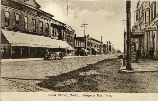 View of Cedar Street looking northwards. Bassett's Drugstore is on the right, and the General Store is directly across the street. Caption reads: "Cedar Street, North, Sturgeon Bay, Wis."