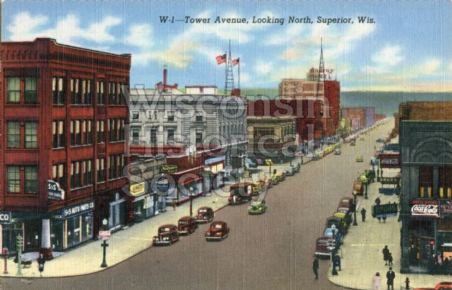 View of Tower Avenue, looking north. A drugstore is on the corner (right), as well as an auto parts store.
