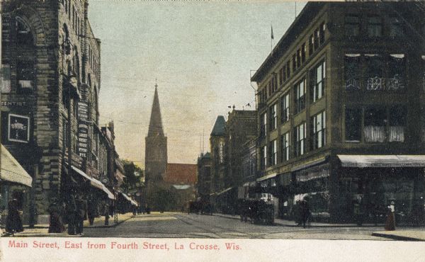 A view of Main street, looking east from Fourth Street. It is interesting to note that "The Largest Whiskey House" saloon is located next door to a drug store.