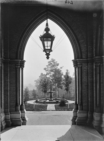 View out of entrance to the National Soldiers Home. Fountain and trees framed by arch with hanging lamp.