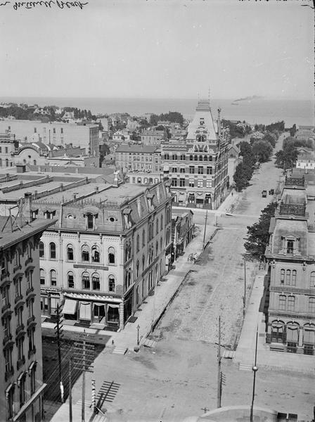 Looking east from Mitchell Block. Elevated view of buildings with the lake and a steamship in the distance.