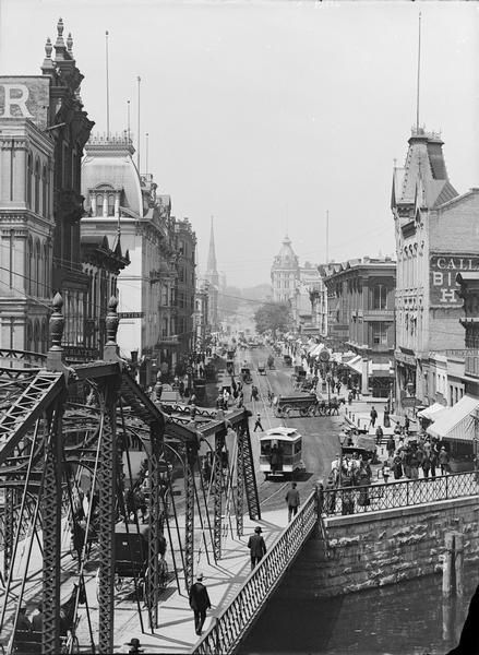 Elevated view of Grand Avenue and a bridge over the river, with streetcar and horse-drawn vehicles on the street.