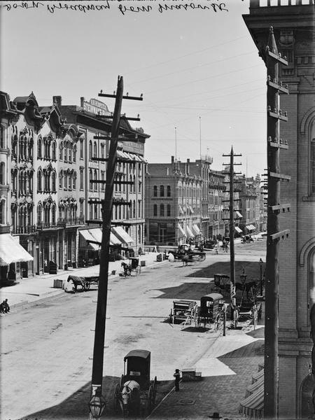 Elevated view down Broadway from Mason Street showing buildings, horse-drawn vehicles, and power lines.