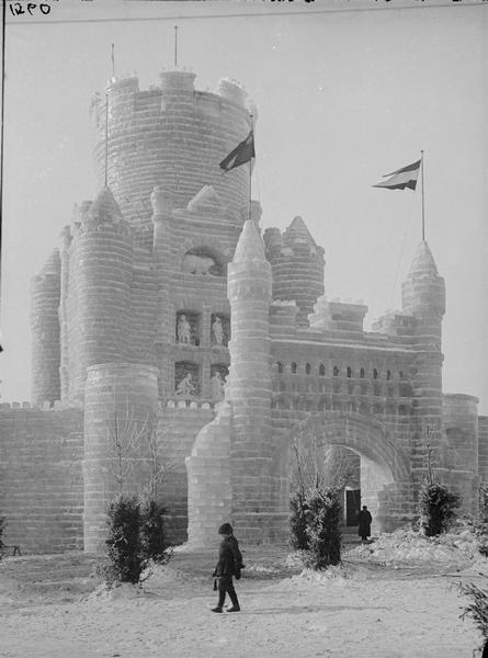 St. Paul Ice Carnival. Main entrance and central tower of ice palace. One person is walking in the foreground, and another person is standing under the entrance arch.