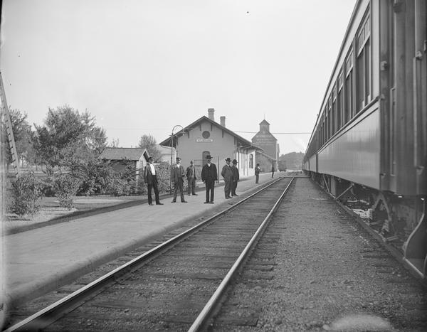 Kilbourn railroad station and train, with several men standing on the platform.